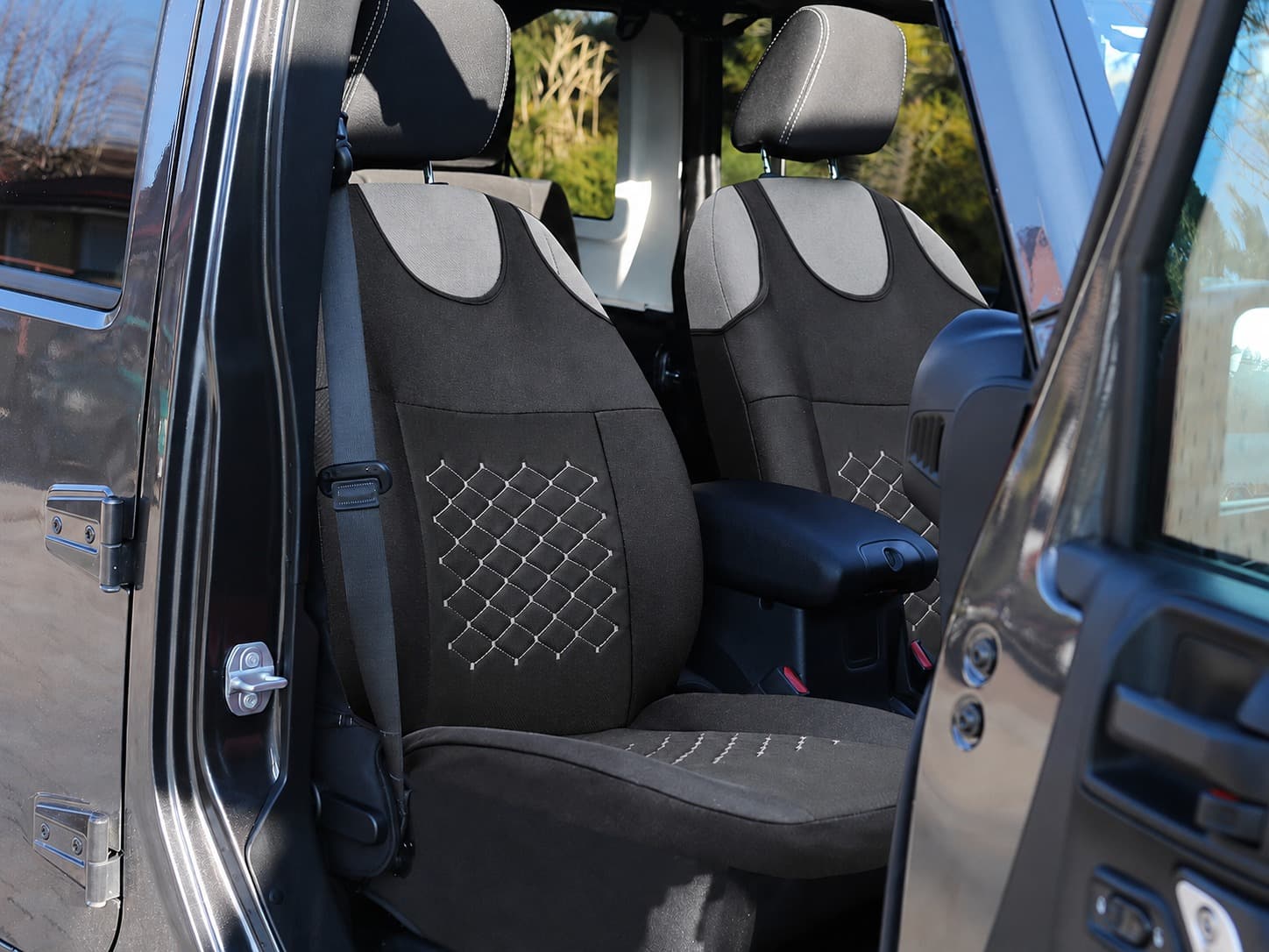 Fundas de asiento tipo camiseta Motive negras con costuras grises montadas en los asientos delanteros de un coche