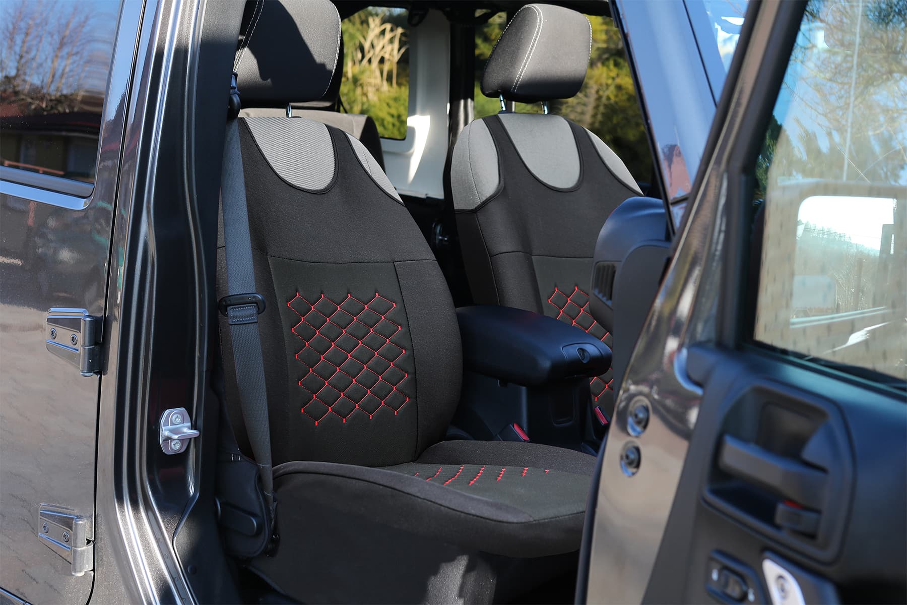 Fundas de asiento tipo camiseta Motive negras con costuras rojas montadas en los asientos delanteros de un coche
